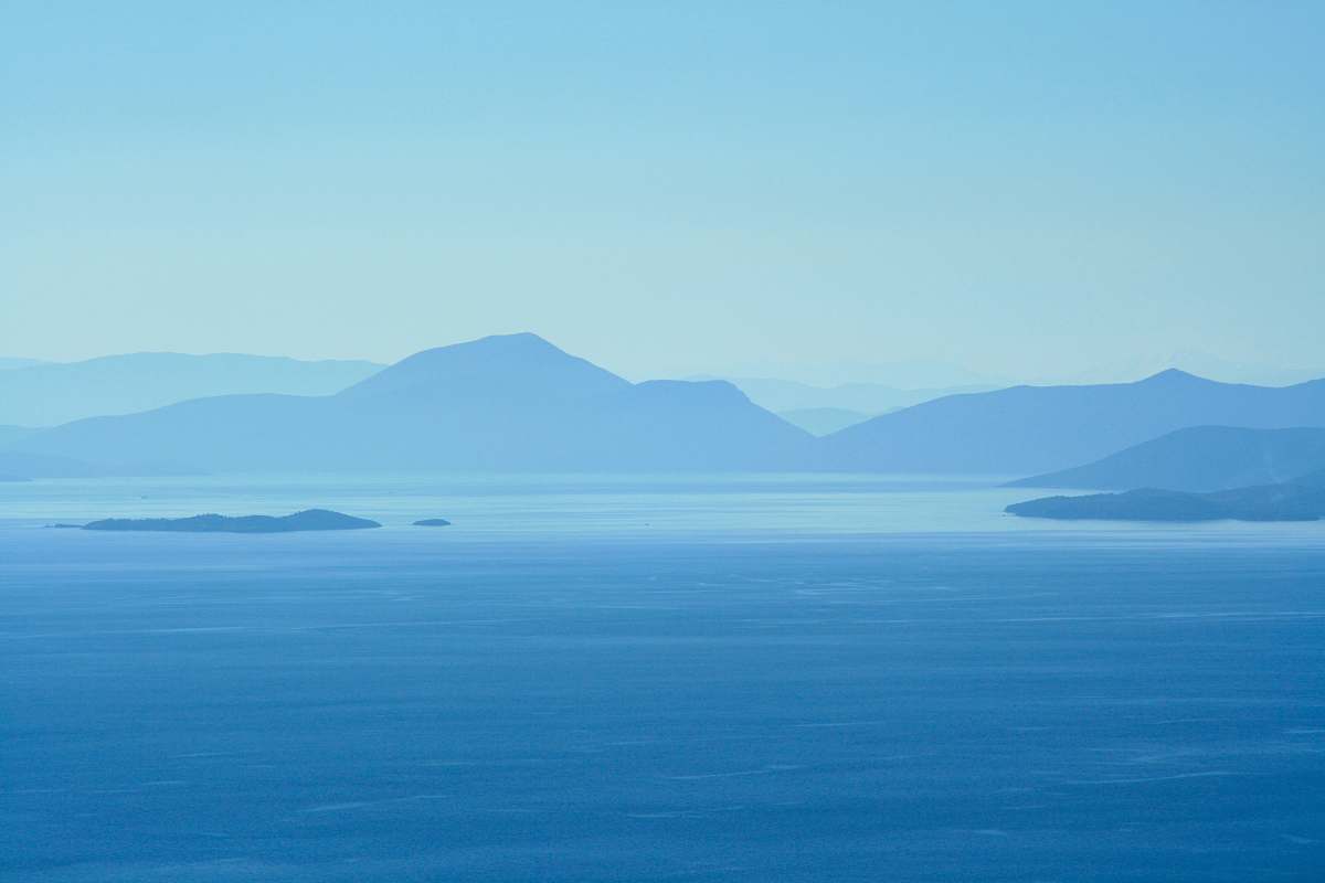 blue calm water beside mountains at daytime island