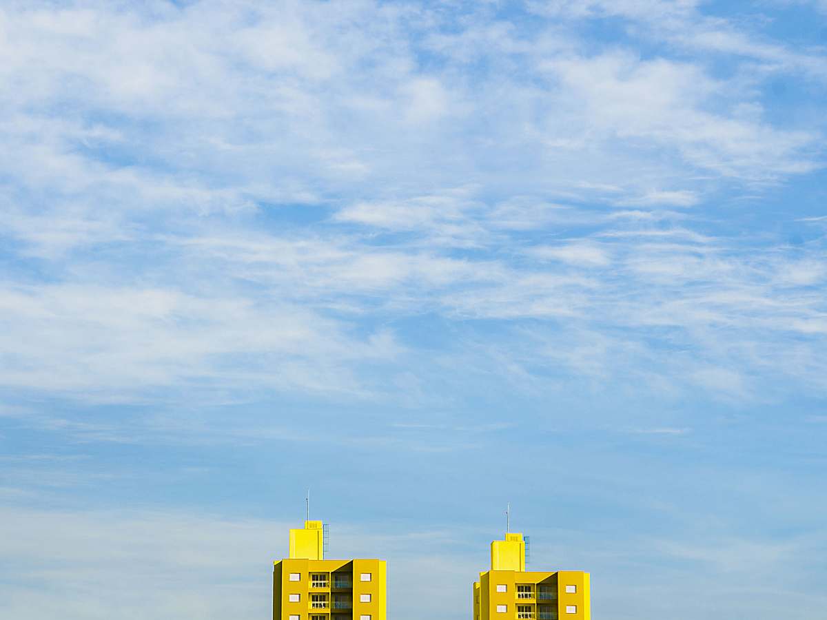 blue close up photography of two yellow buildings cloud