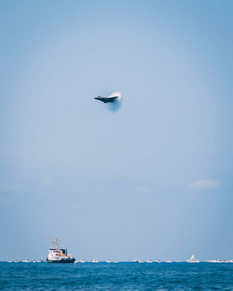 vehicle jet fighter creating sonic boom over the sea with ships boat