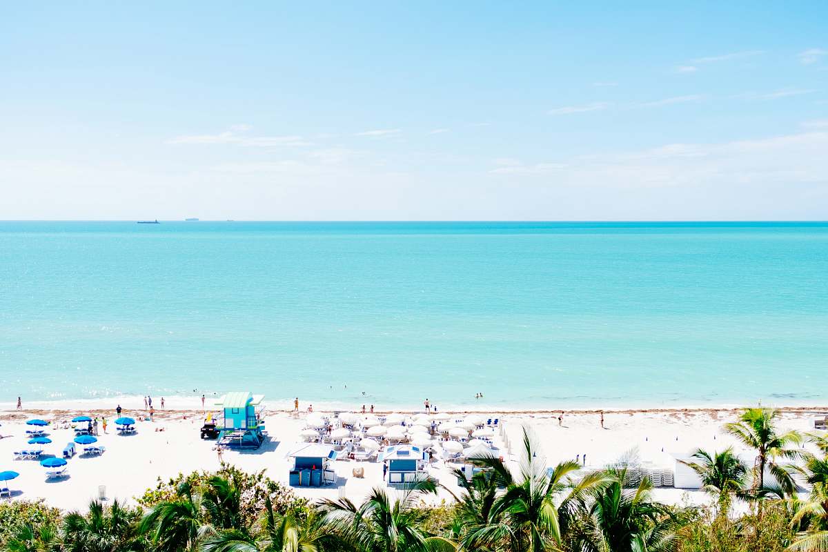 ocean white sand beach with stalls under blue sky sea