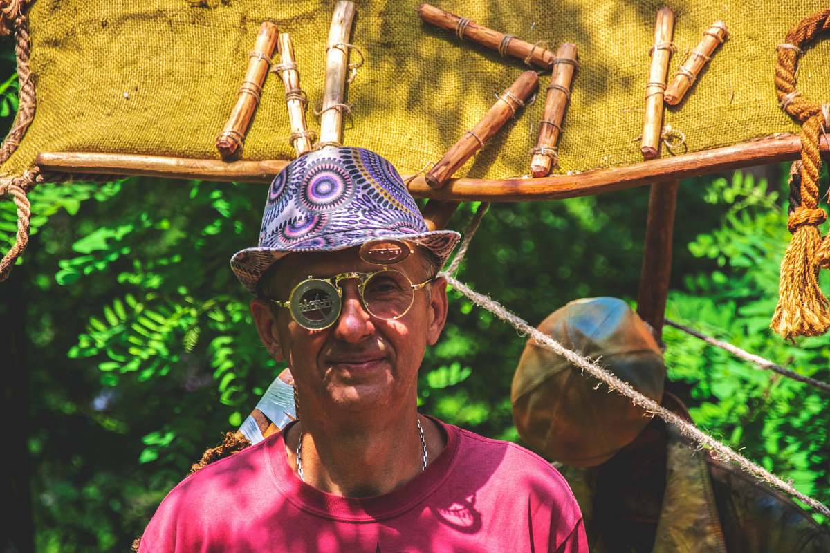clothing man wearing purple hat near trees and brown signage human