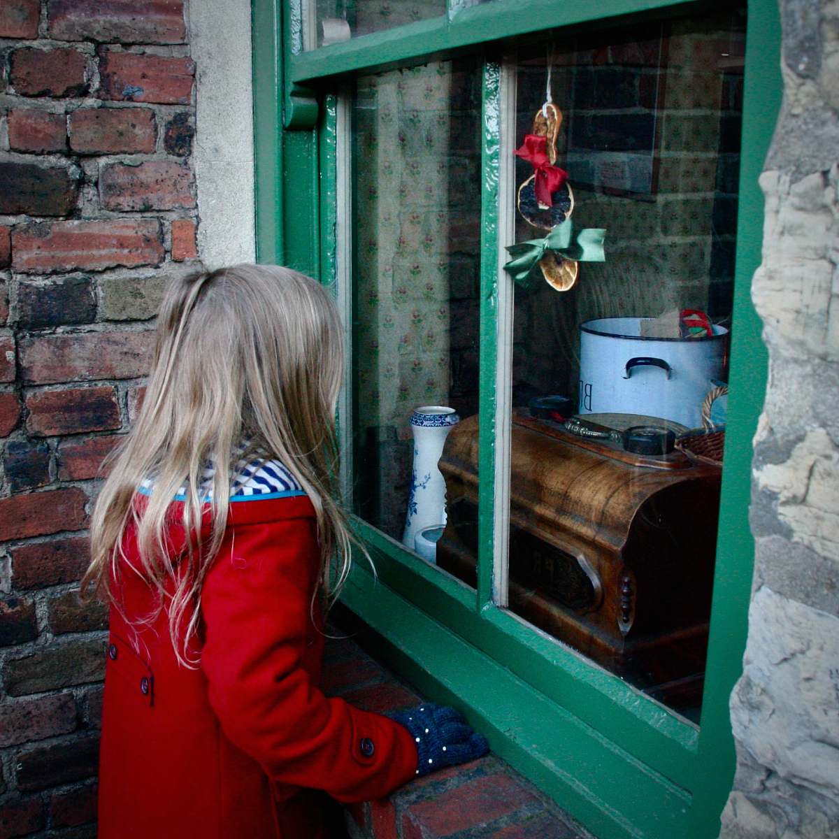 child girl near glass window red coat