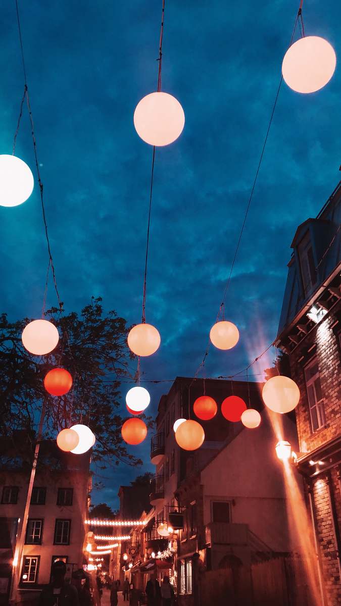 person lighted multicolored lanterns hanging over street lighting