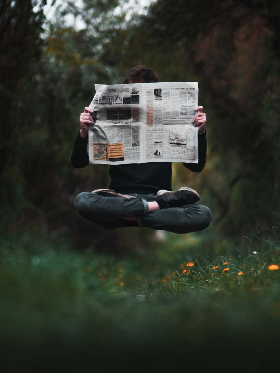 newspaper person holding a news paper during daytime text