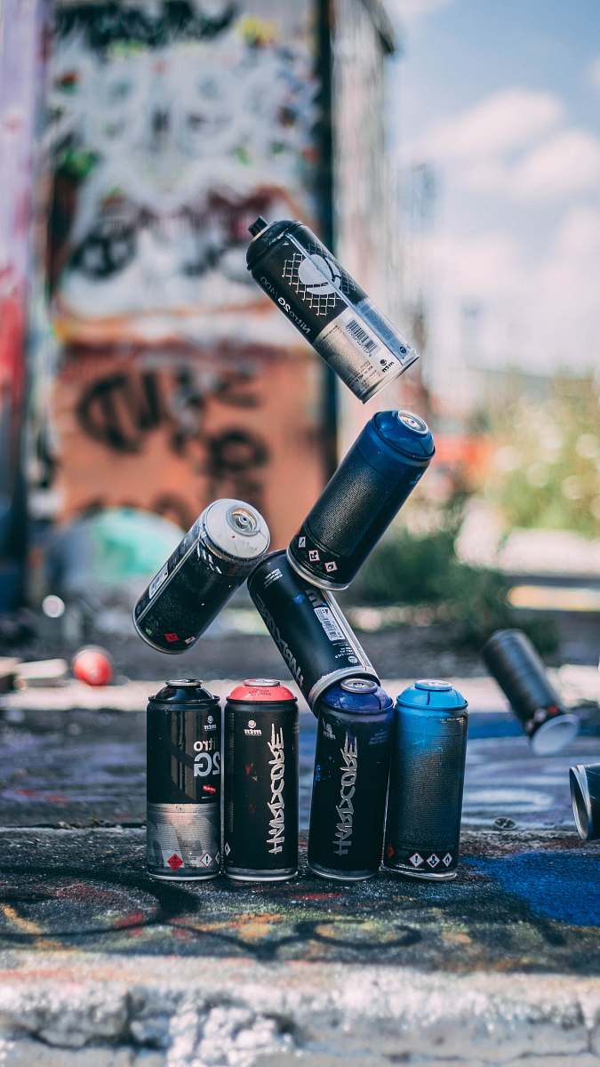 people selective focus photo of flying spray paint cans o person