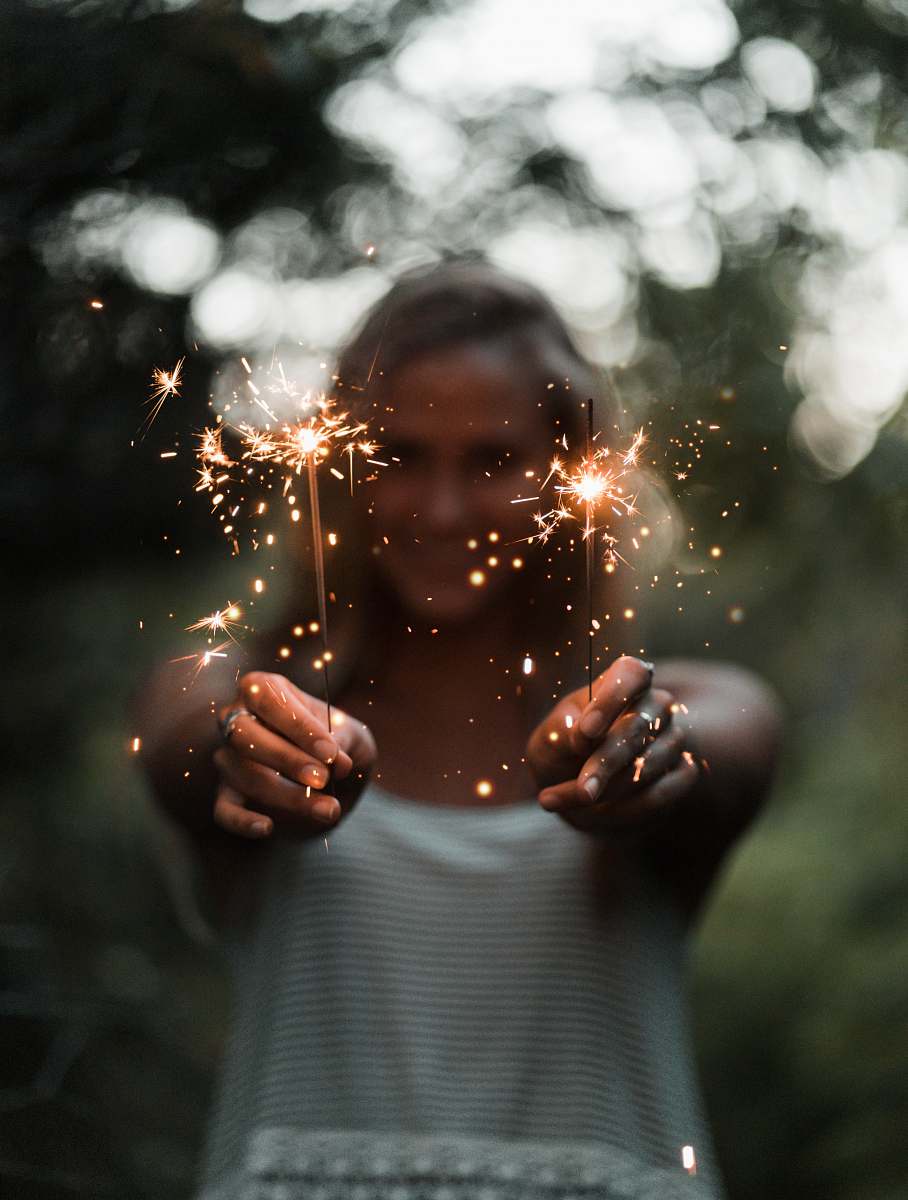 person selective focus photography of woman holding two sparklers people