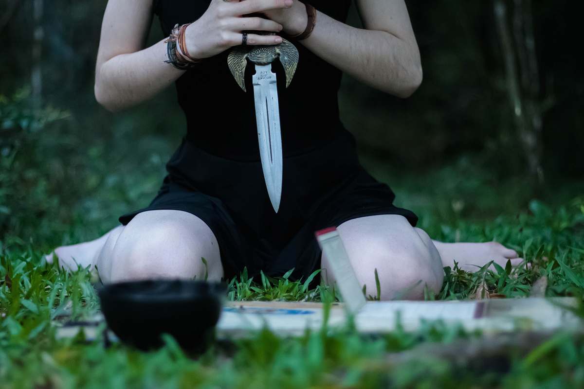 person woman kneeling on grass holding knife finger