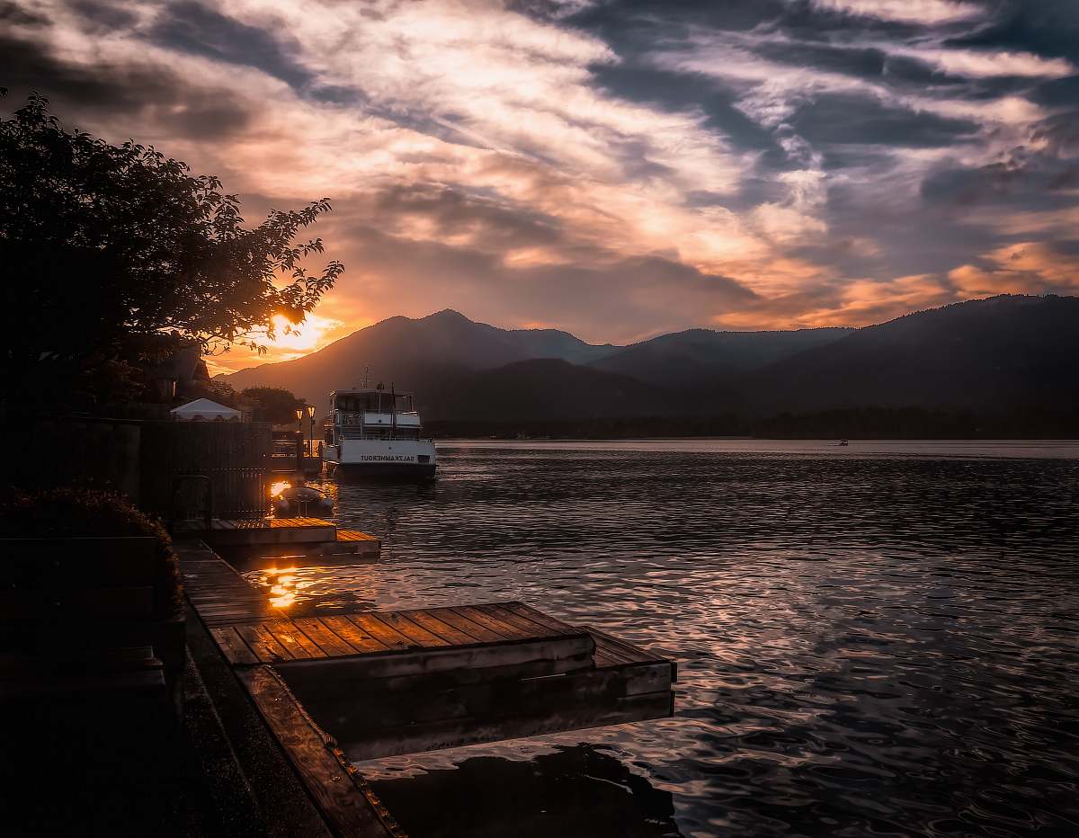 sunset boat on body of water near mountain austria
