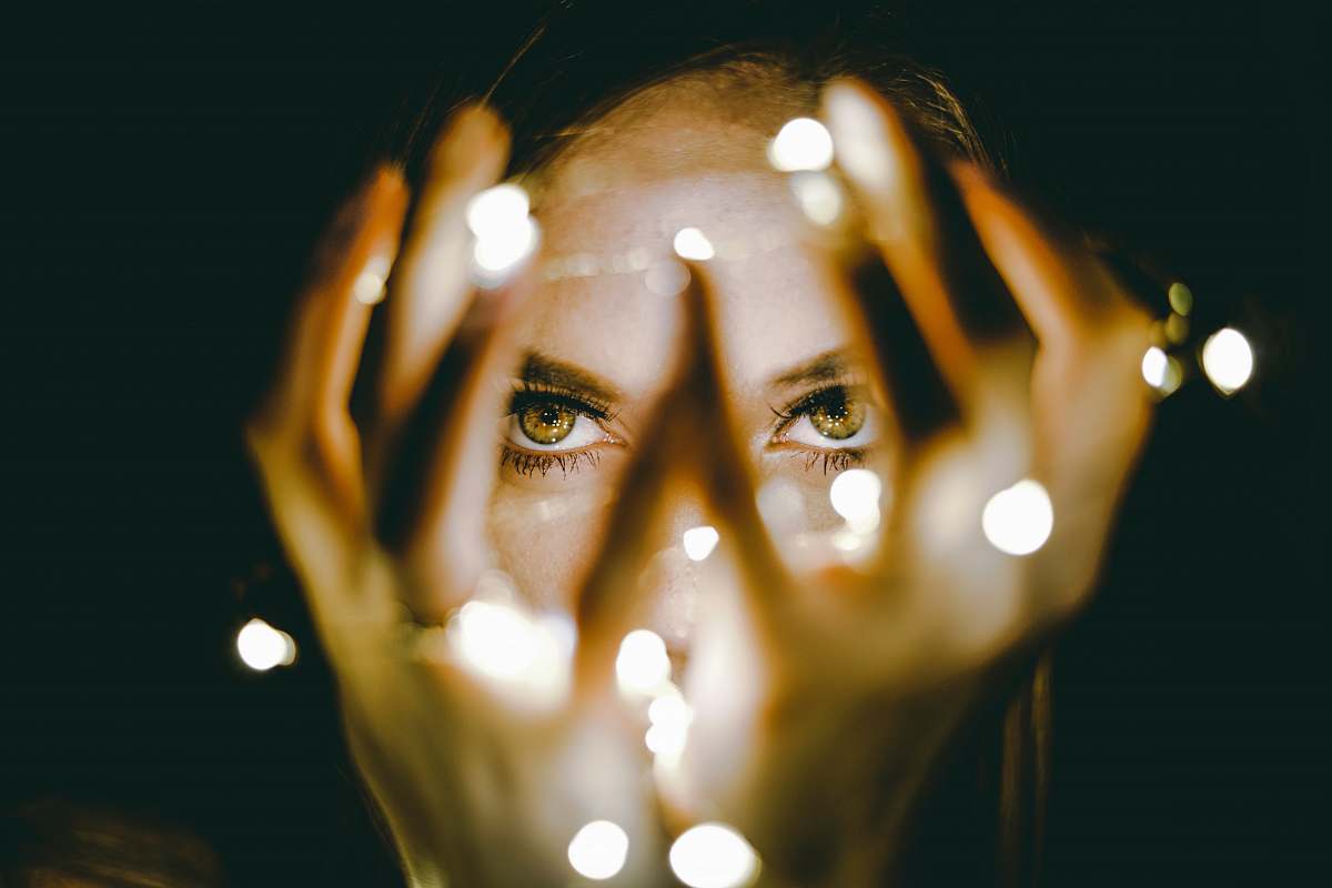 light woman holding string lights eyes