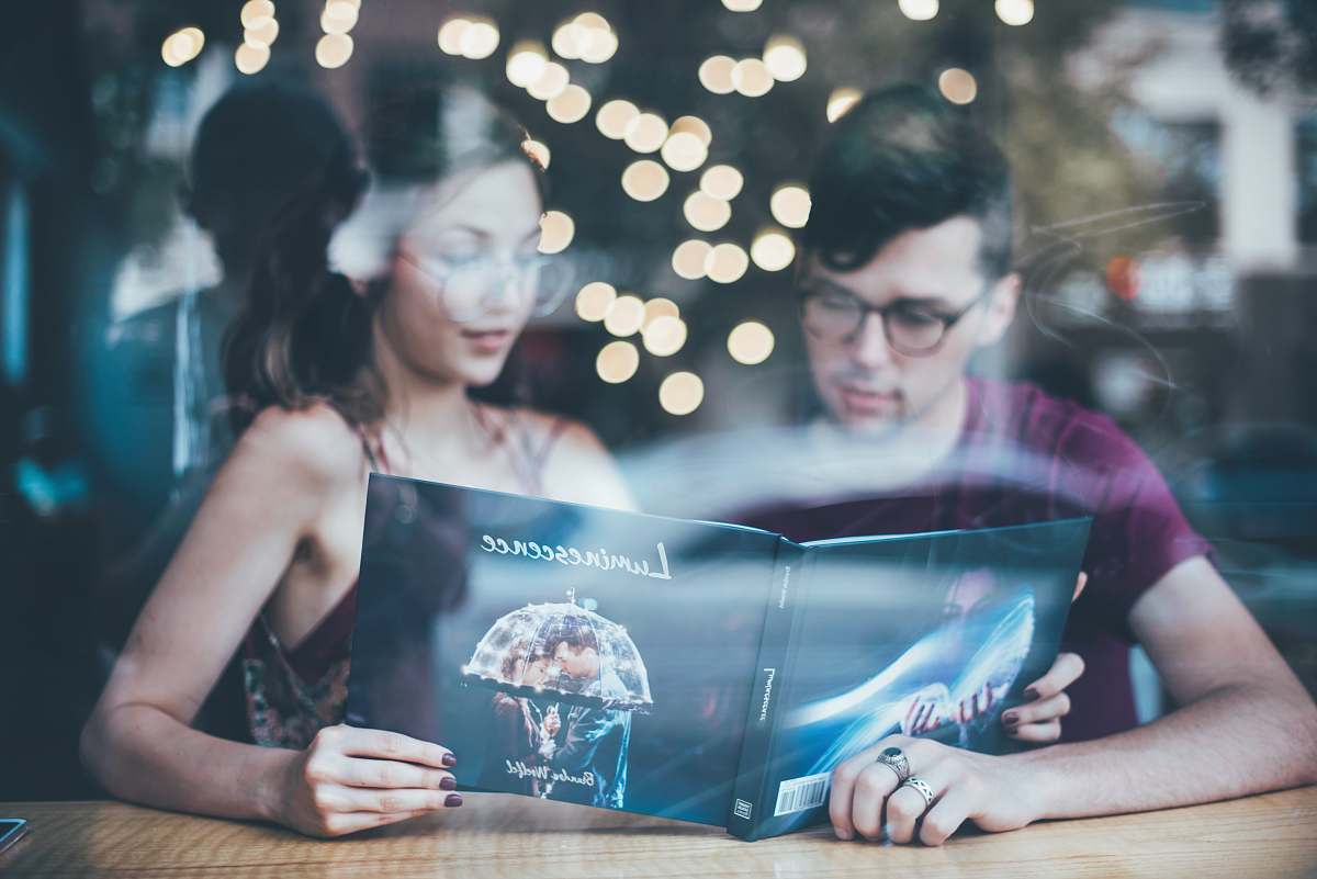 human man sitting beside woman while reading people