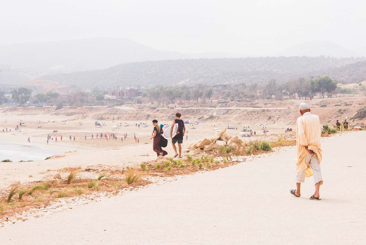 human man wearing brown coat walking on brown road people