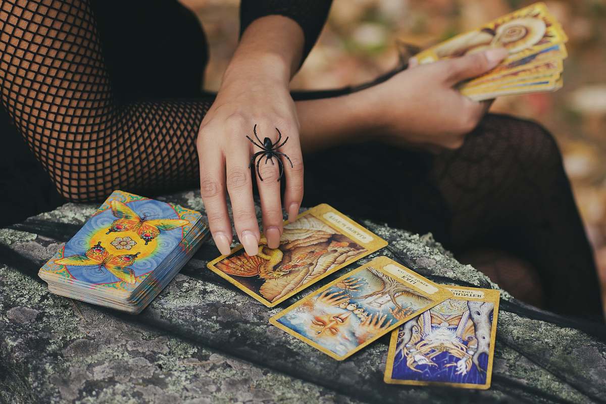human woman holding tarot cards finger