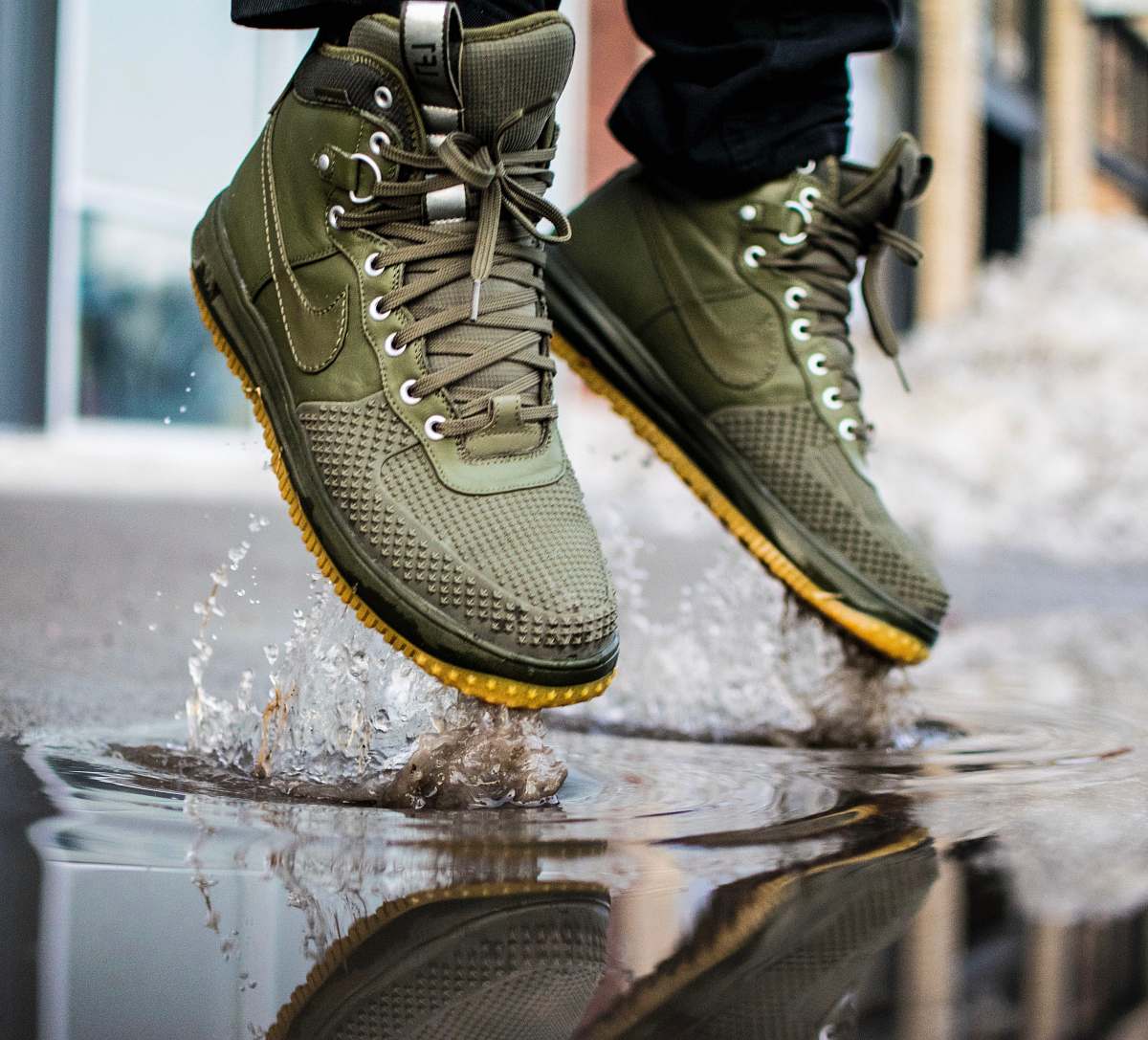 footwear person wearing green Nike sneakers jumping on water boot