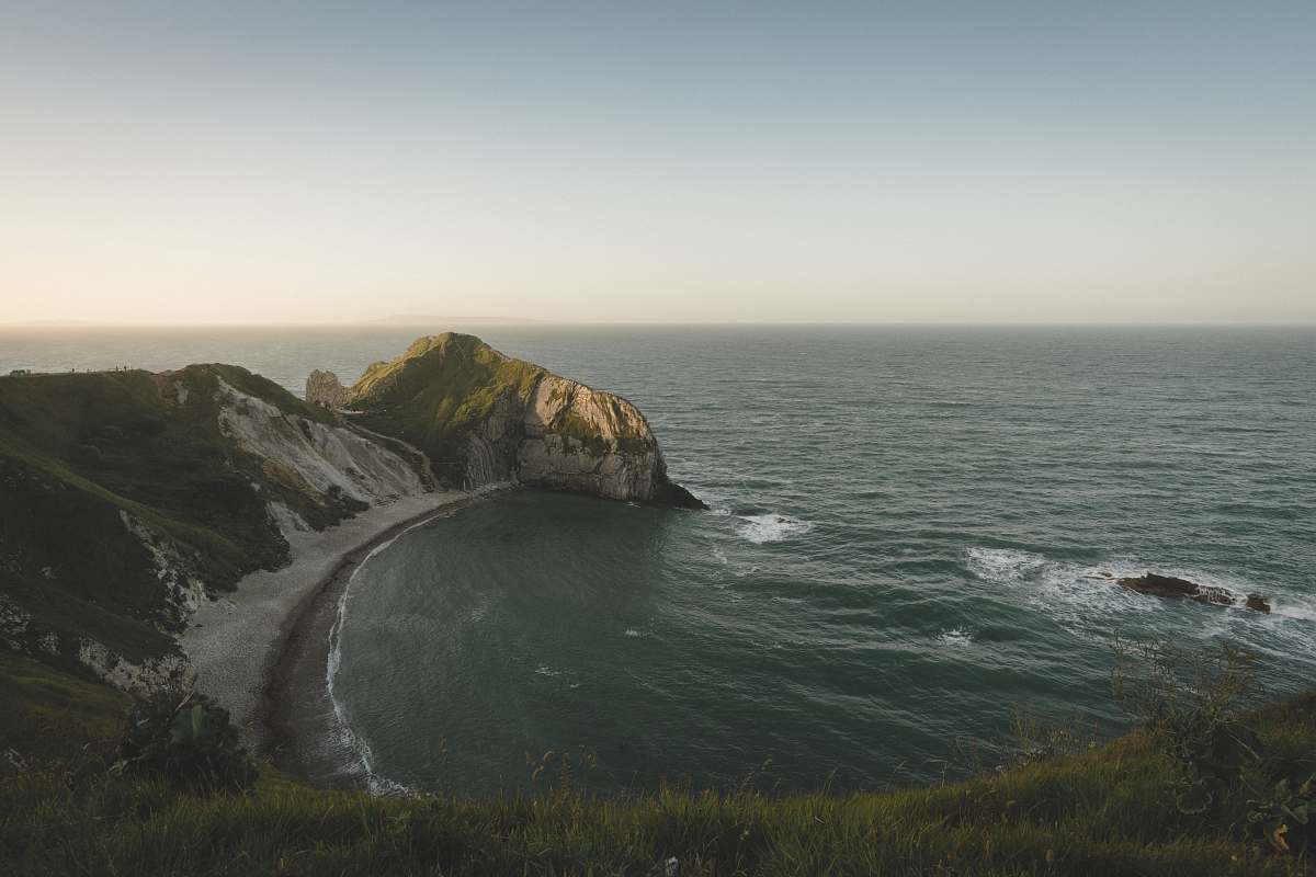 cliff aerial photography of green body of water and mountain united kingdom