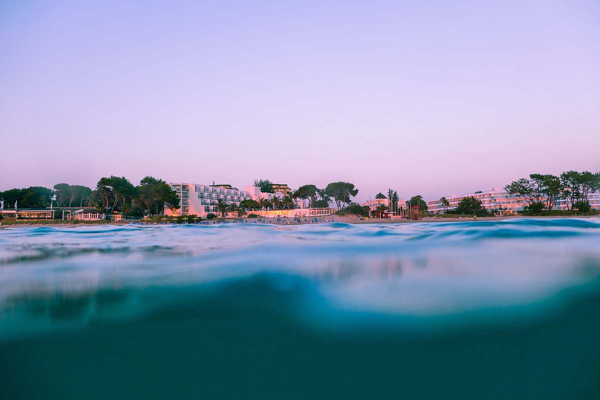 hotel body of water near buildings and trees under blue sky at golden hour ocean