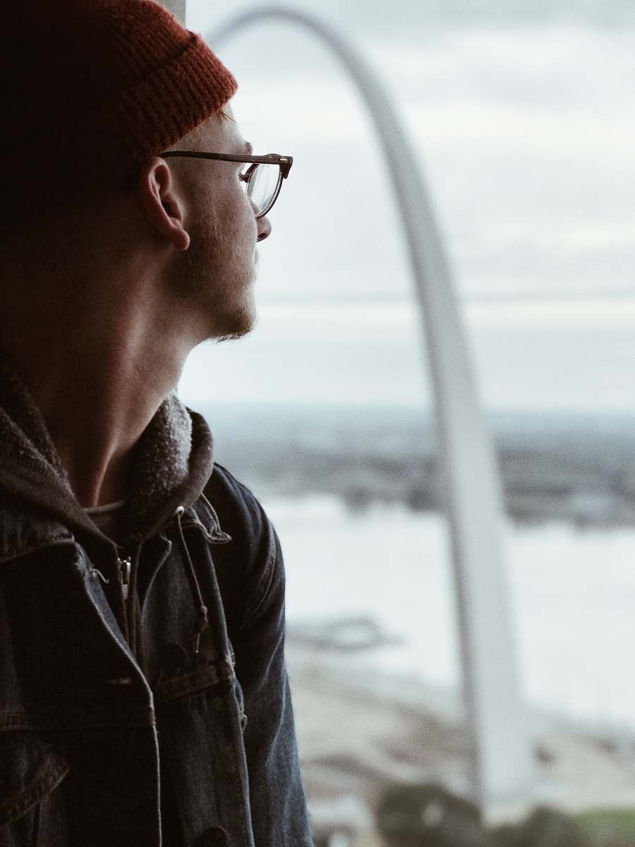 clothing man in denim jacket standing beside window looking outside jacket