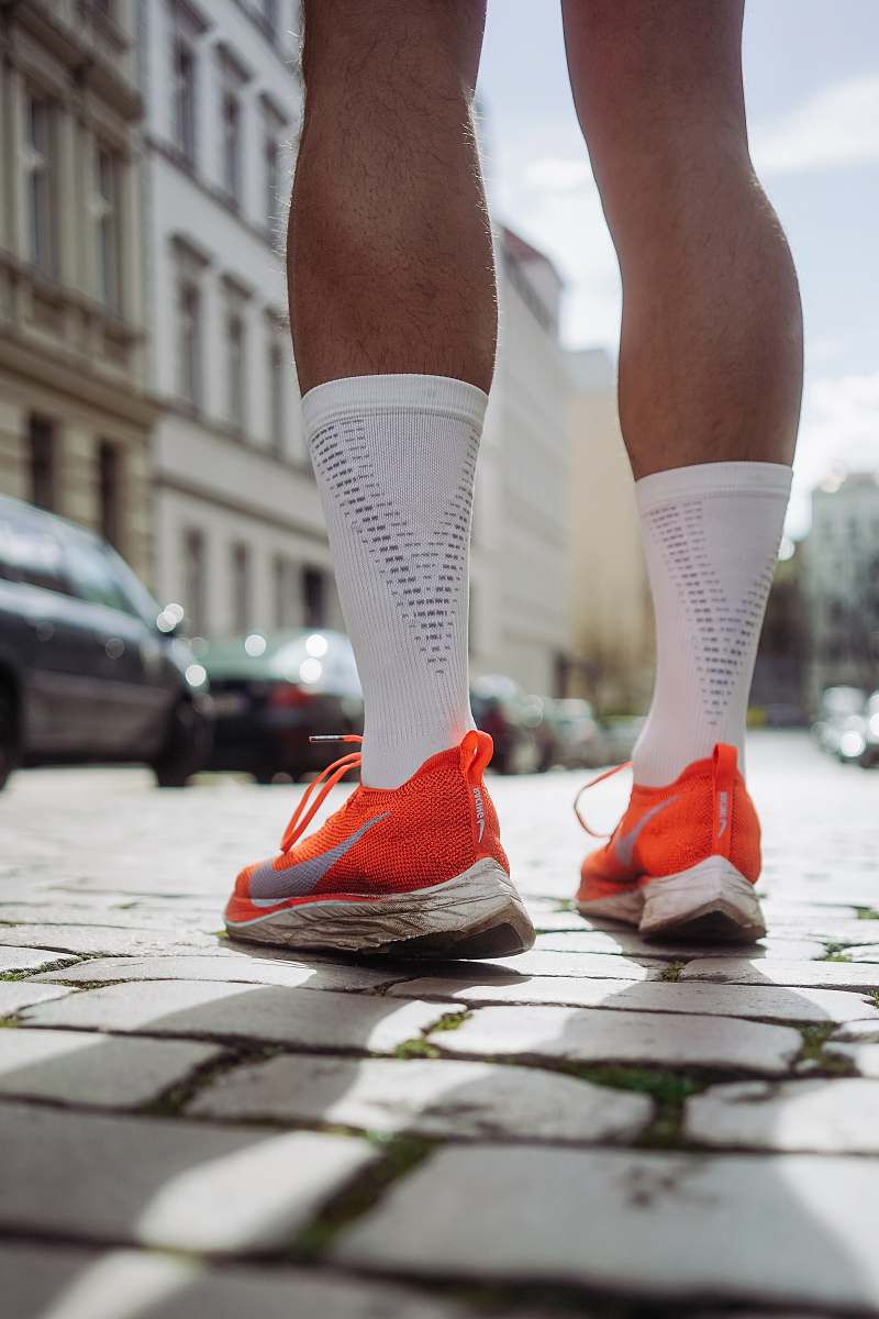 clothing person wearing orange Nike running shoes standing on pavement shoe