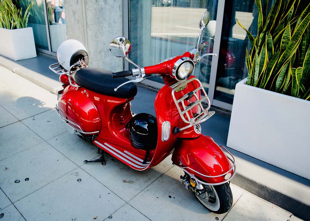 clothing red motor scooter parked near glass door helmet