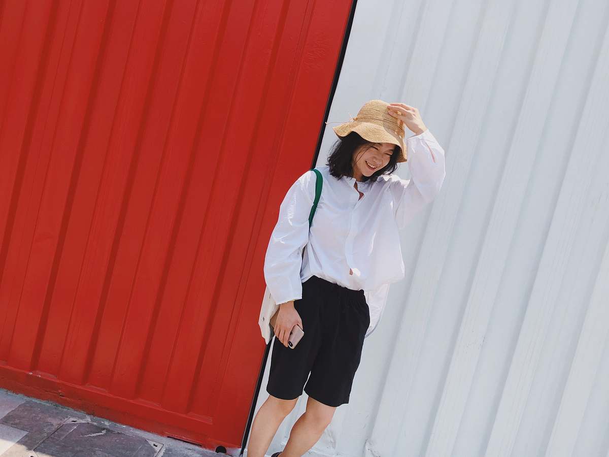 clothing smiling woman standing beside red and white wall human