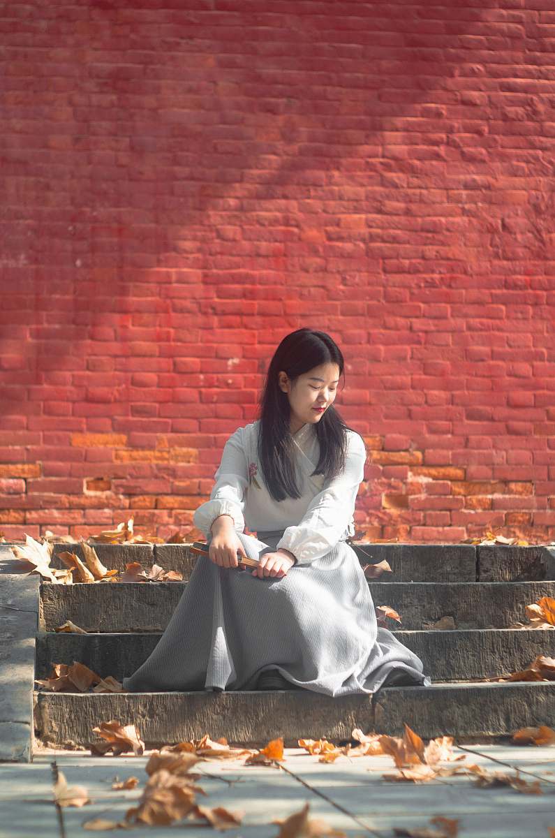 clothing woman sitting on gray stair near leaves during daytime animal