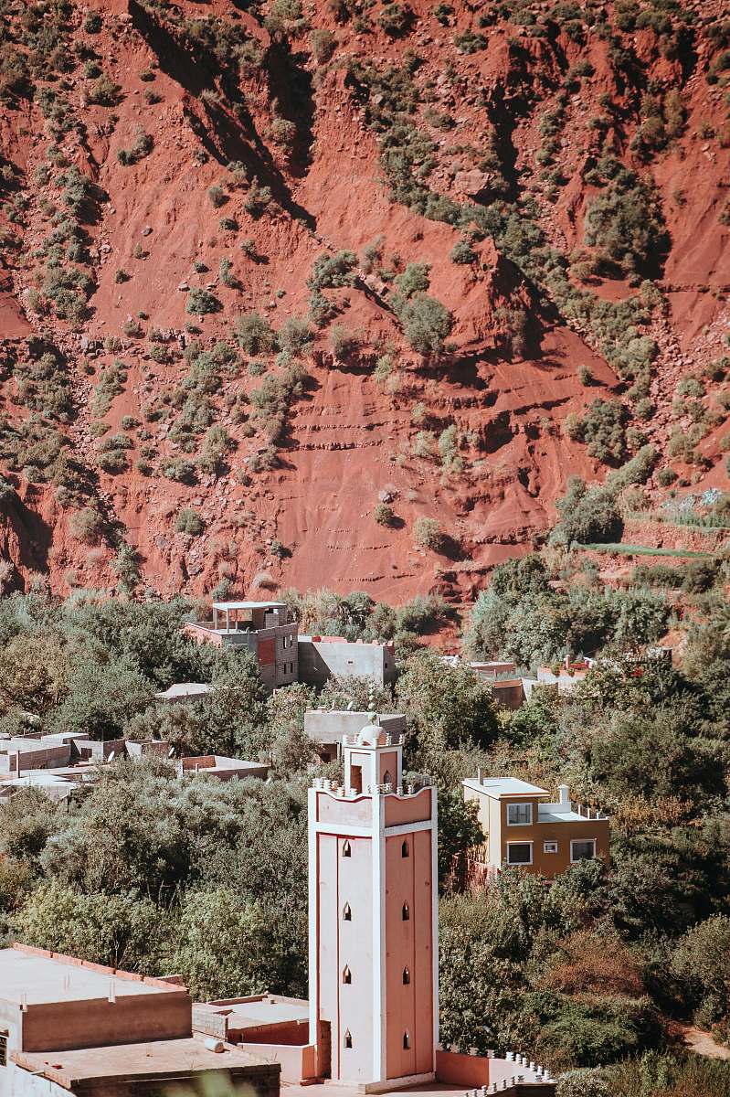 building brown concrete buildings near tress and brown rocky hill tower