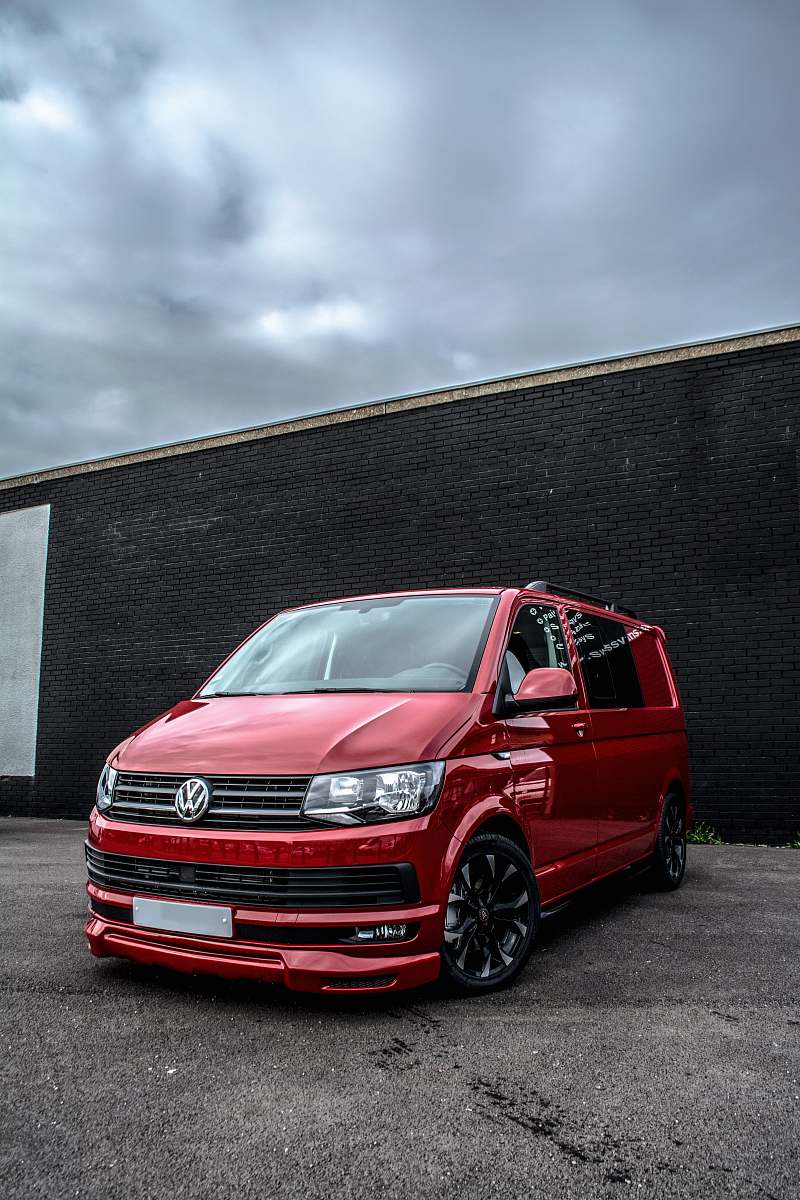 car red Volkswagen Caravelle parked beside black cocnrete building coupe