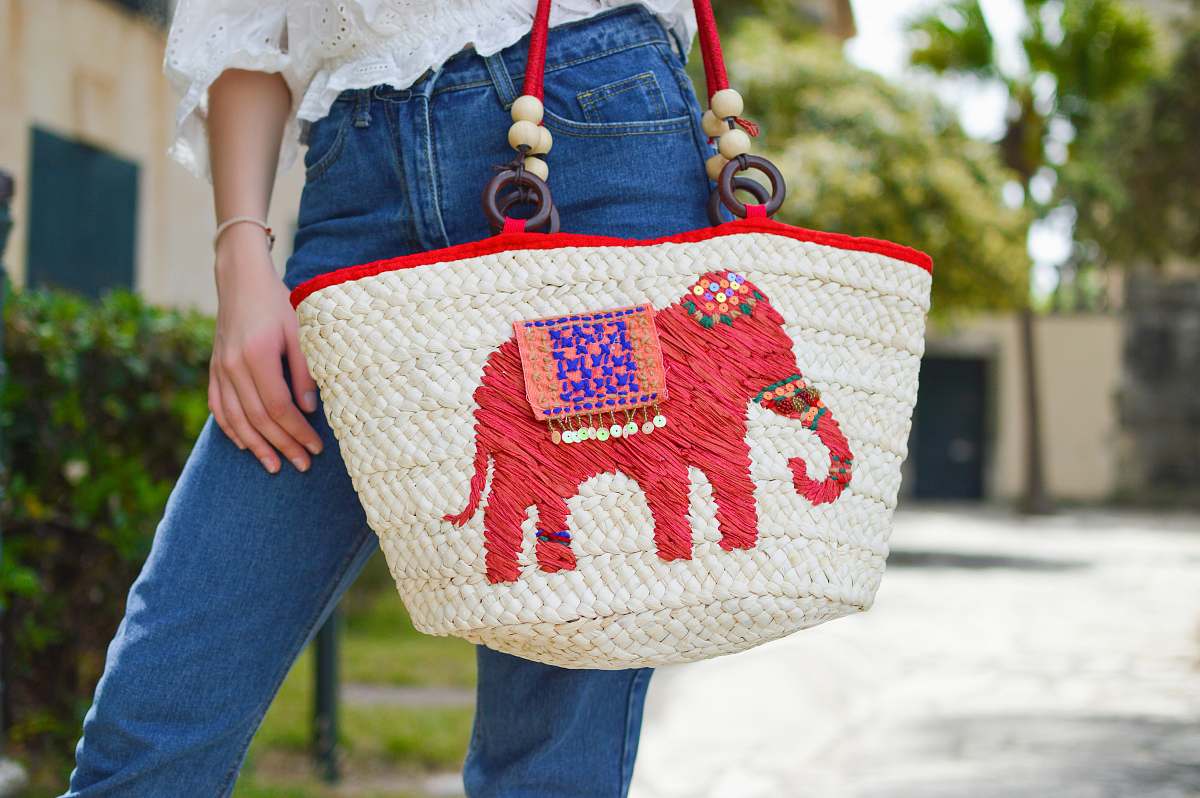 purse person holding white and red elephant graphic tote bag close-up photo accessories