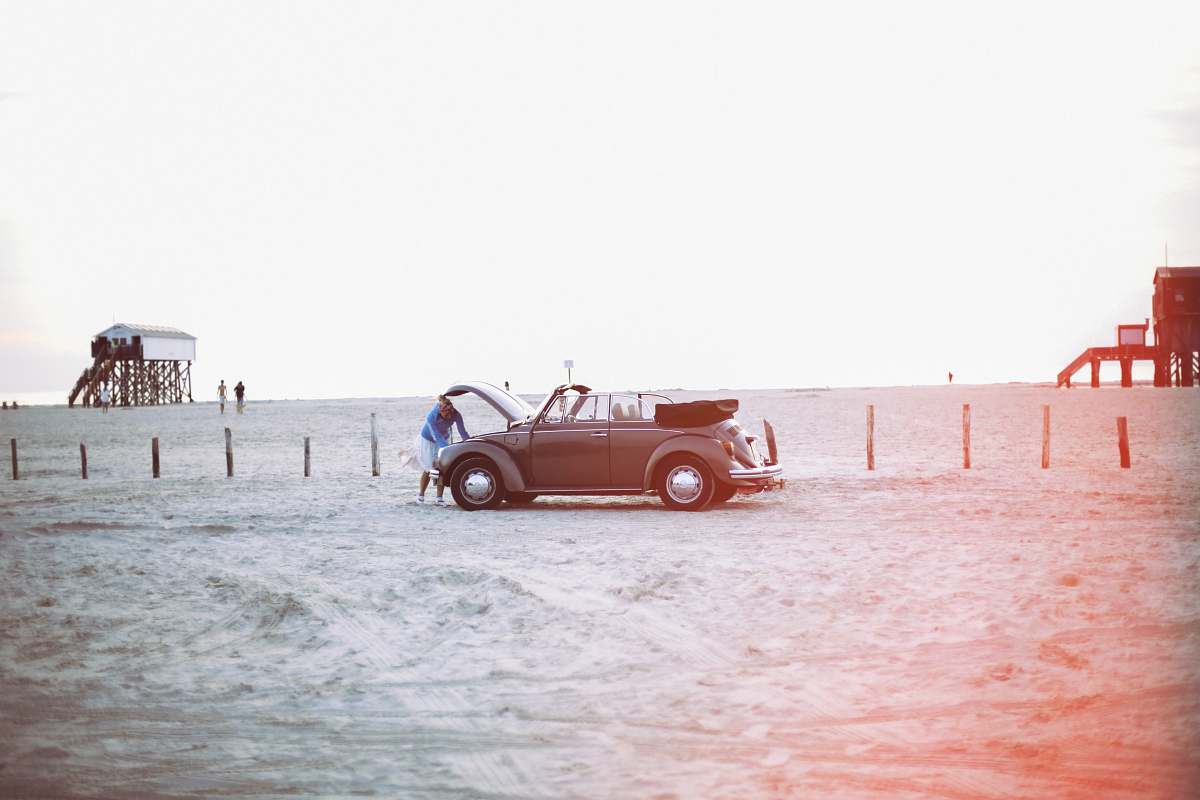 car woman looking to vehicle engine near peoples at daytime sand