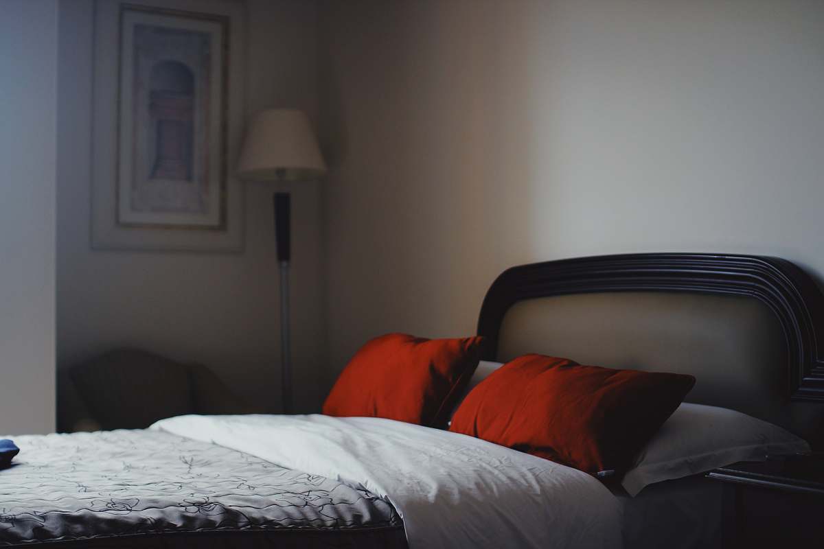 furniture two red pillows and gray and white floral bedspread room