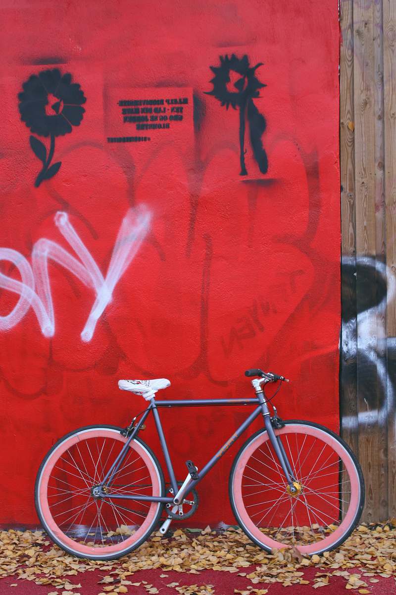 bike black and red bike leaning near red wall vehicle