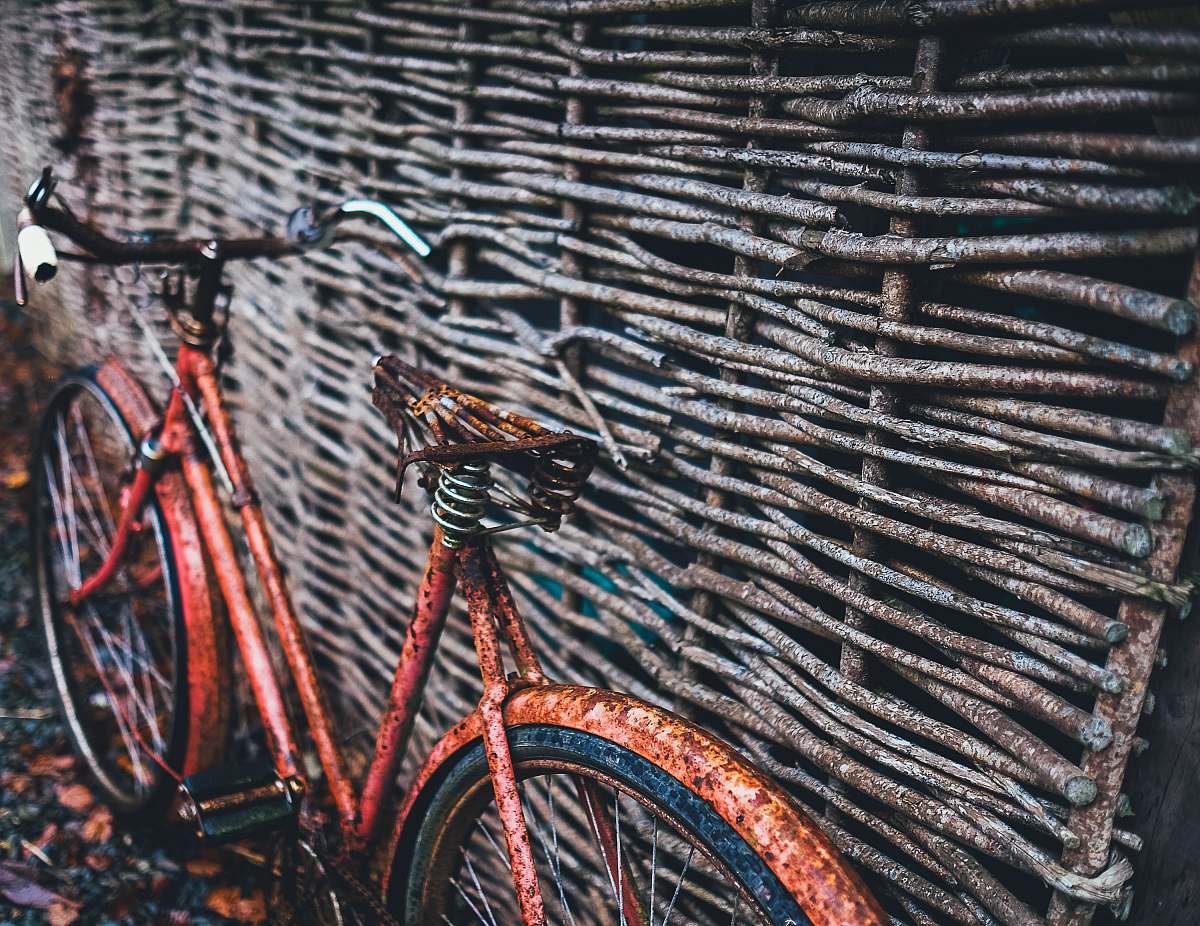 bike red bicycle parked beside brown wood wall at daytime rusty