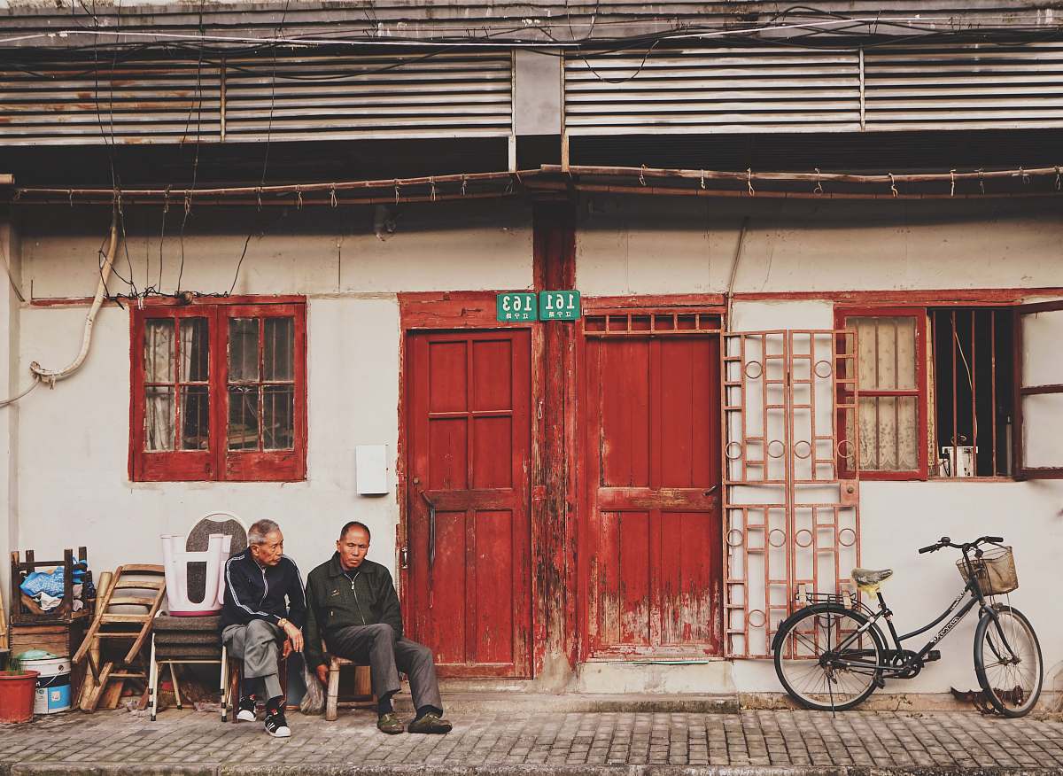 bike two men sits beside brown wooden door during daytime chair