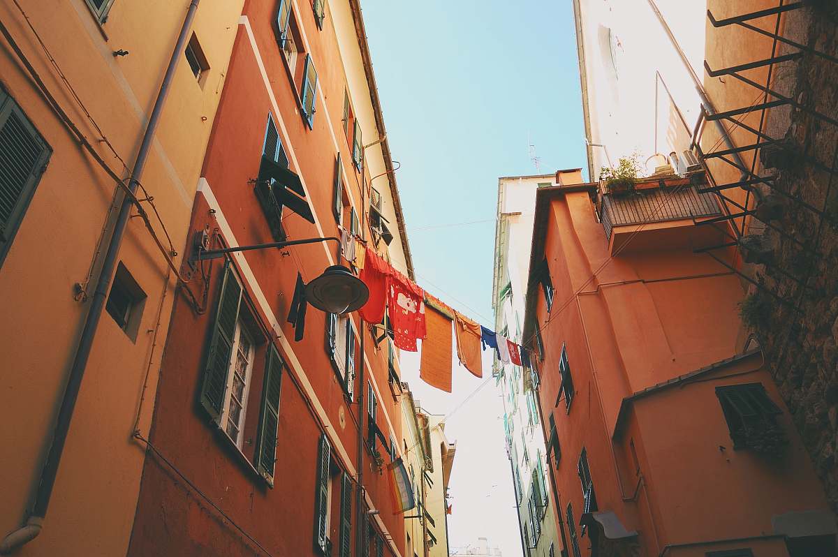 city assorted-color textiles hanged on clothes dryer in between houses italy