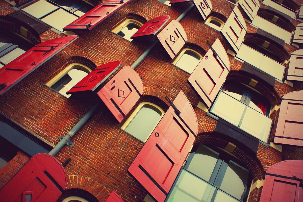 brick brown brick building with opened red wooden windows during daytime windows