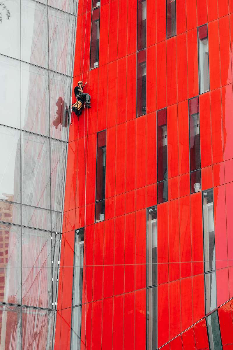 red man climbing on red building wall