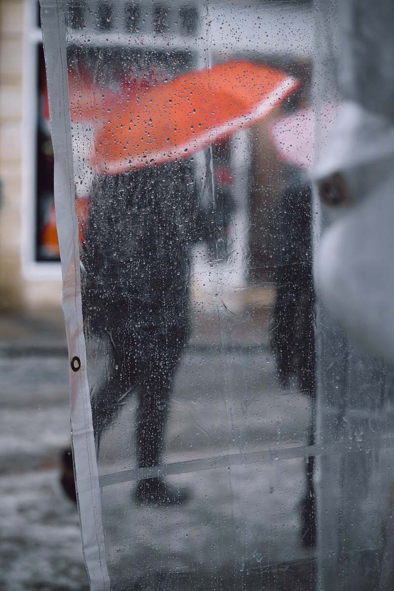walking clear plastic coat with water drops showing people using umbrella asphalt