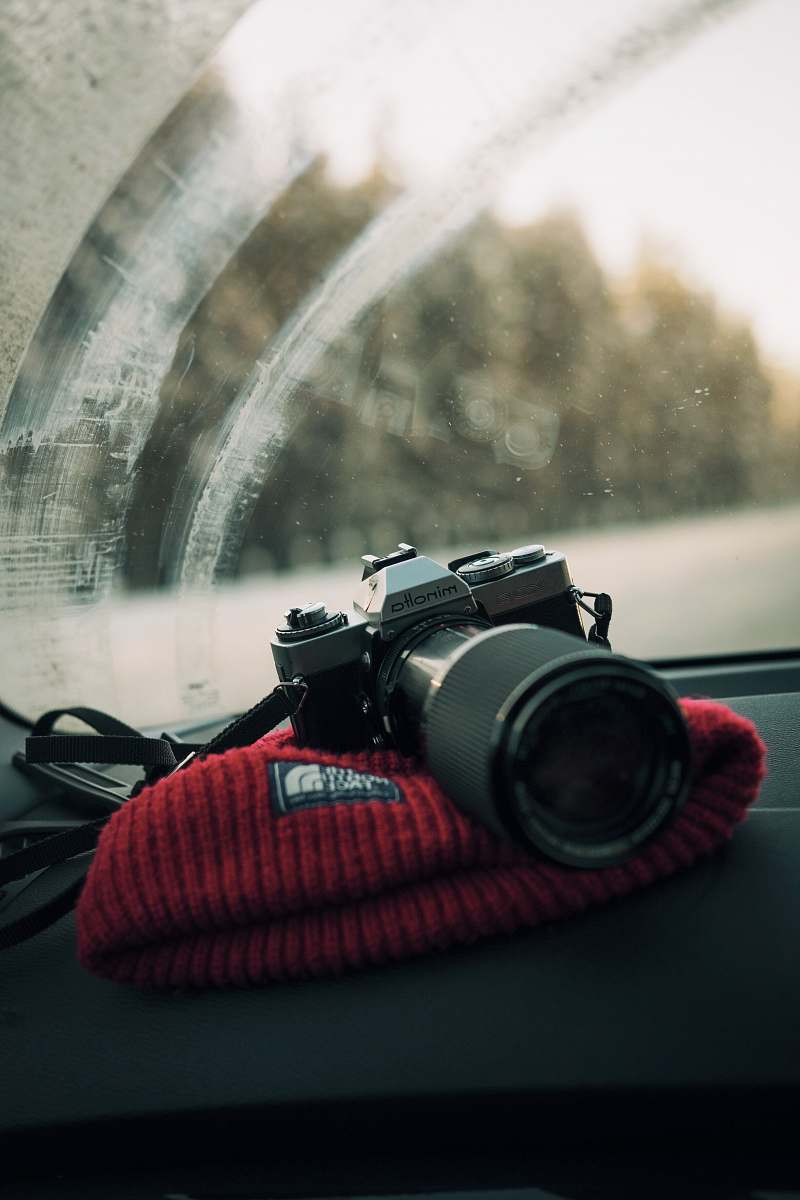 lens photo of gray Minolta DSLR camera on glove compartment minolta