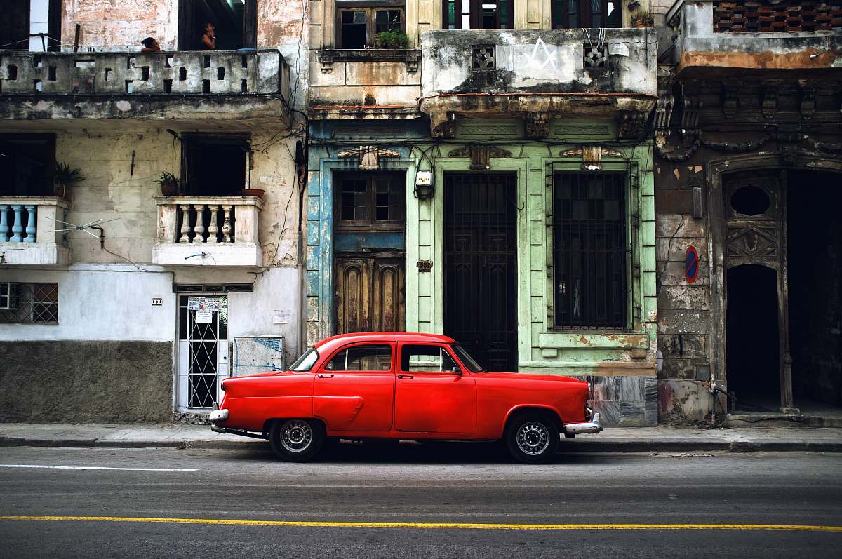 cuba red car parked on road in front concrete building automobile
