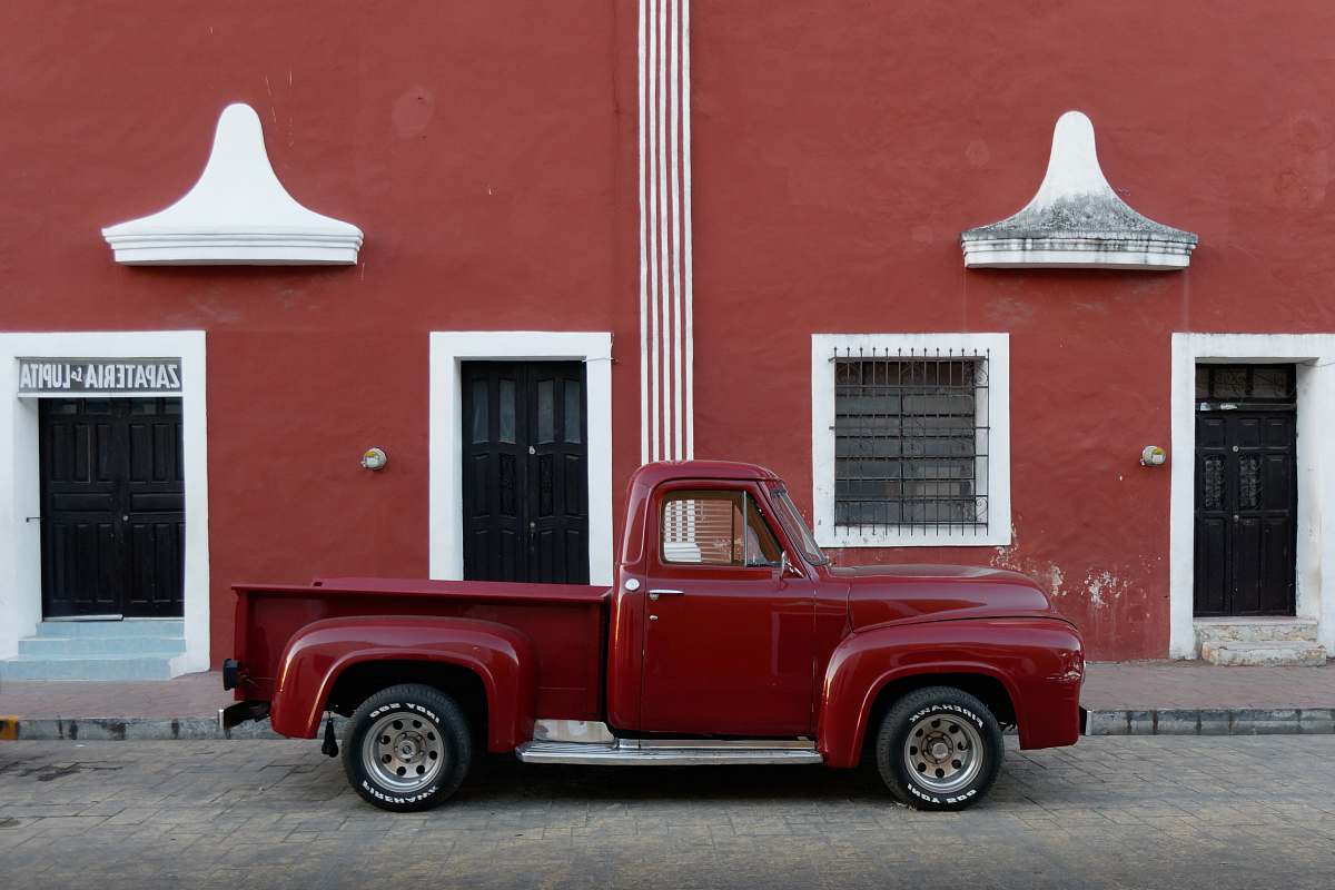 truck red single cab pickup truck parked outside brown builing vehicle