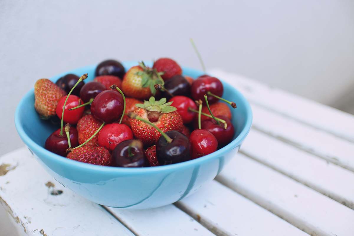fruit focus photography of strawberries and cherries on blue bowl food