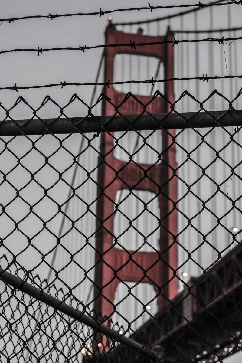 urban photo of diamond link fence near red bridge at daytime chainlink fence