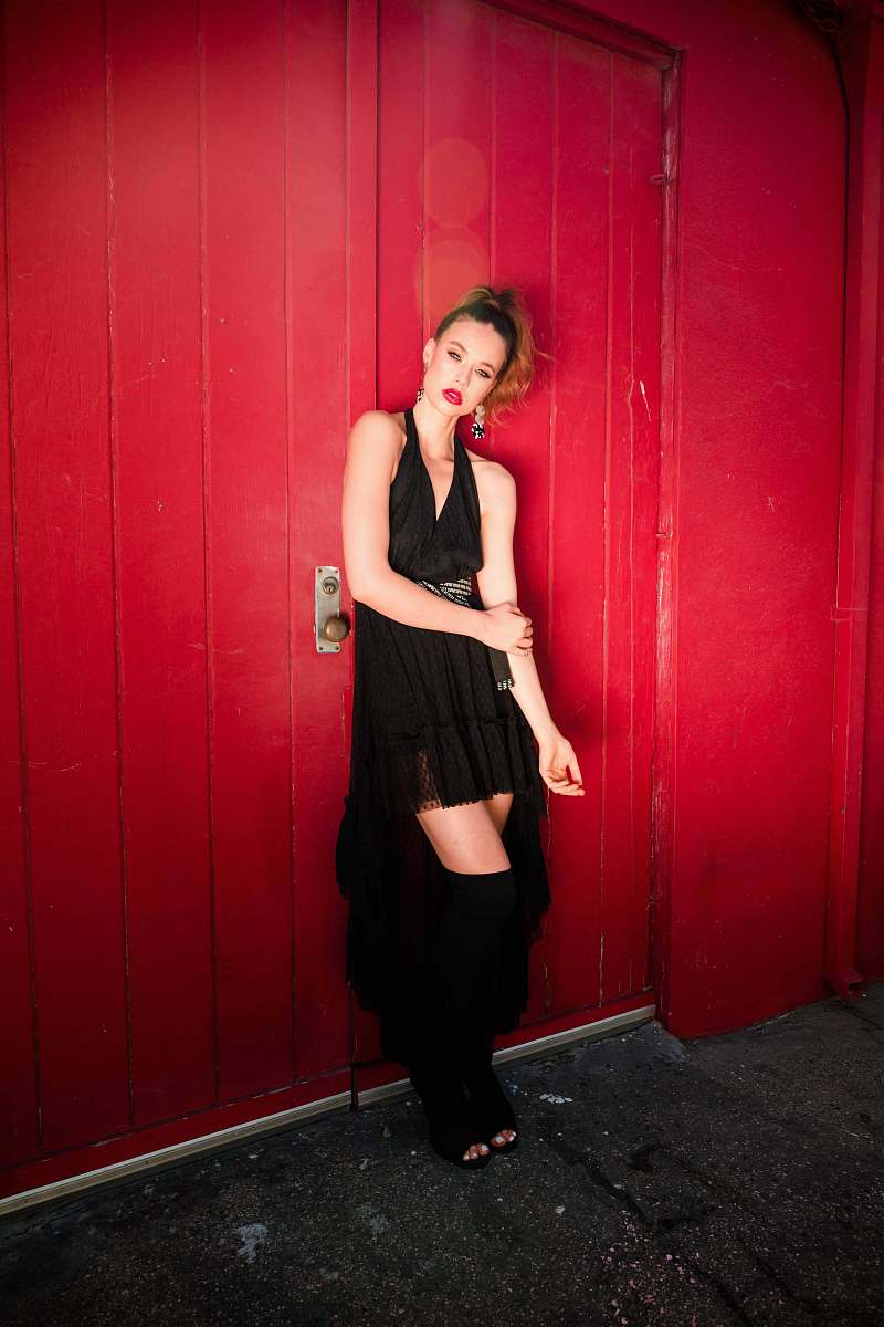 apparel woman standing and leaning on red wall sleeve