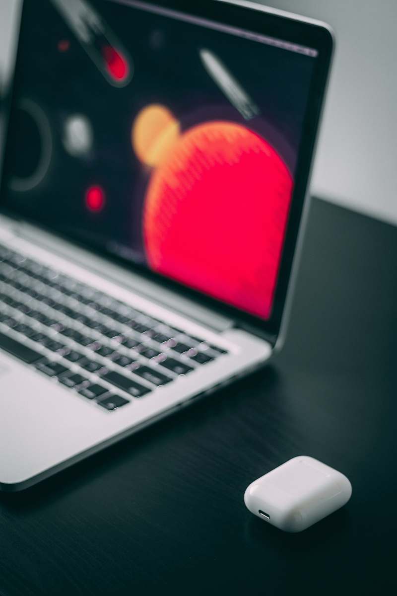 pc turned on Macbook beside Airpods case computer
