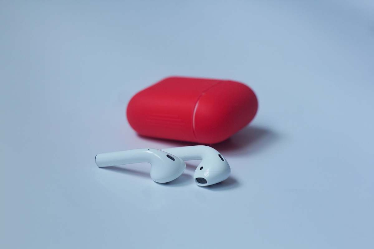 computer white wireless earbuds with red charging case on white surface hardware