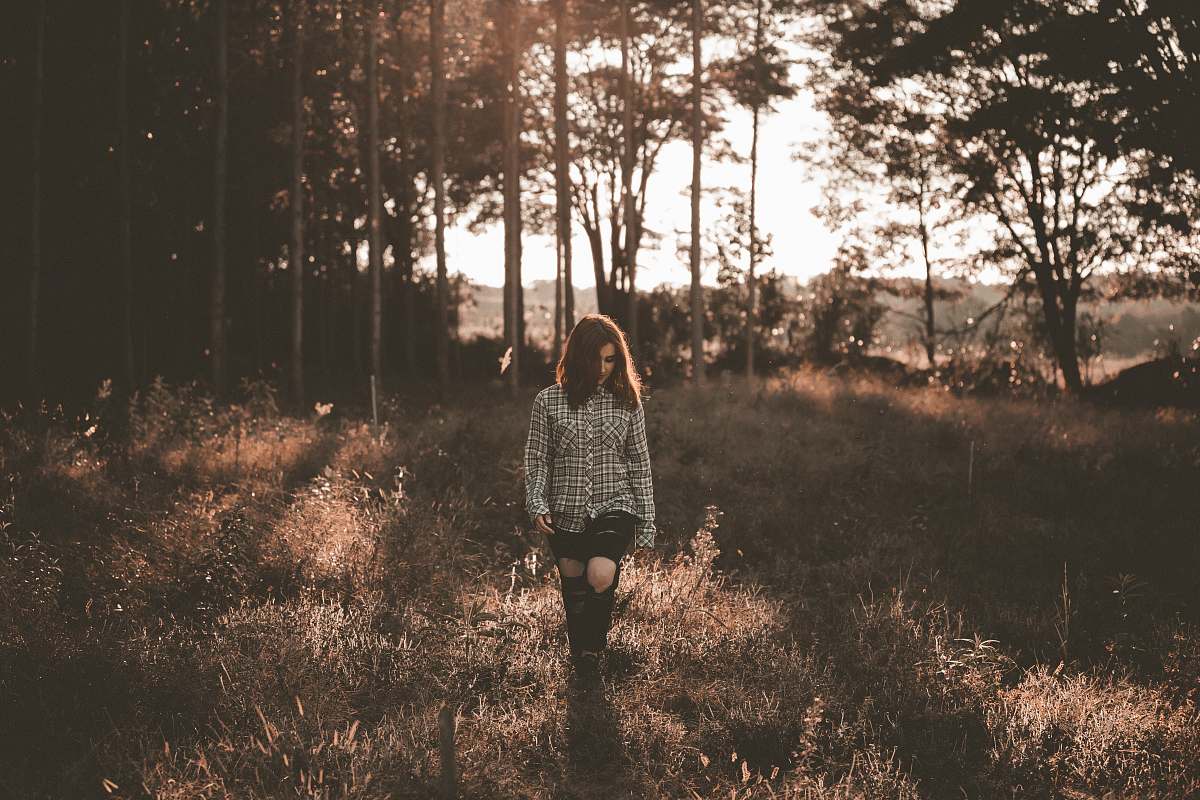 forest woman walking on brown grass field near trees woman