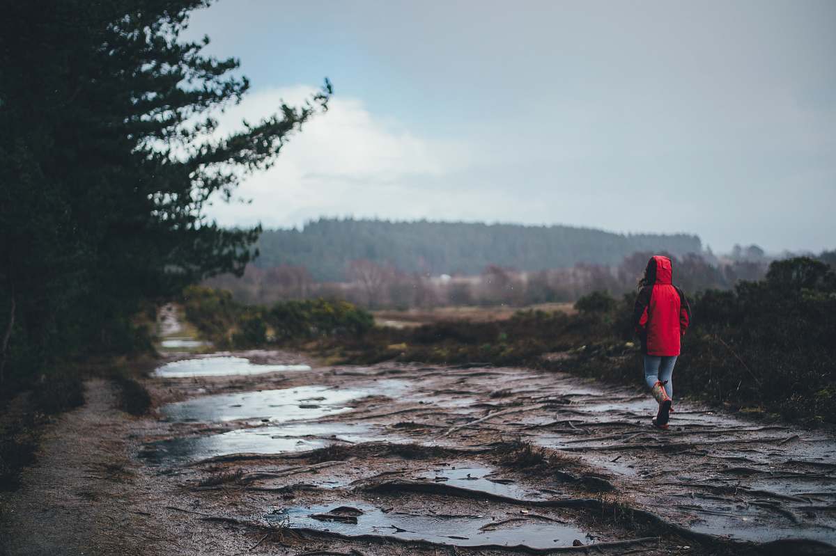 road person standing on brown surface dirt road
