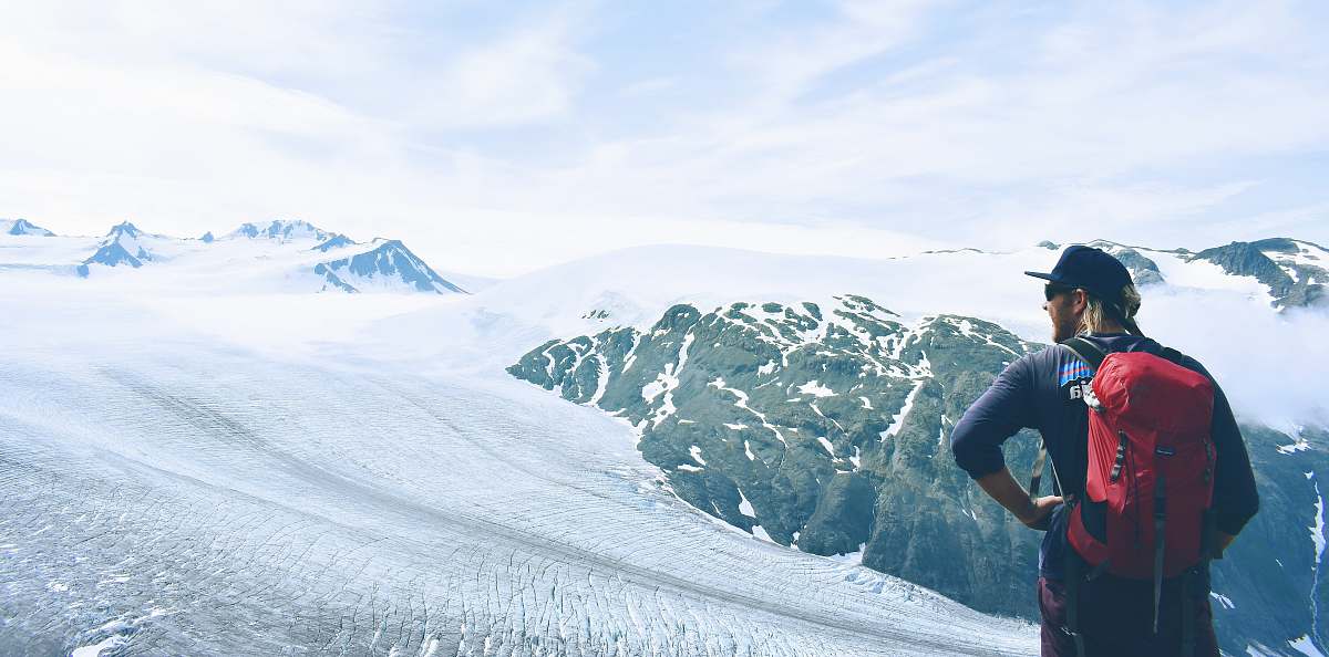 mountain man in red backpack standing on snowy land snow