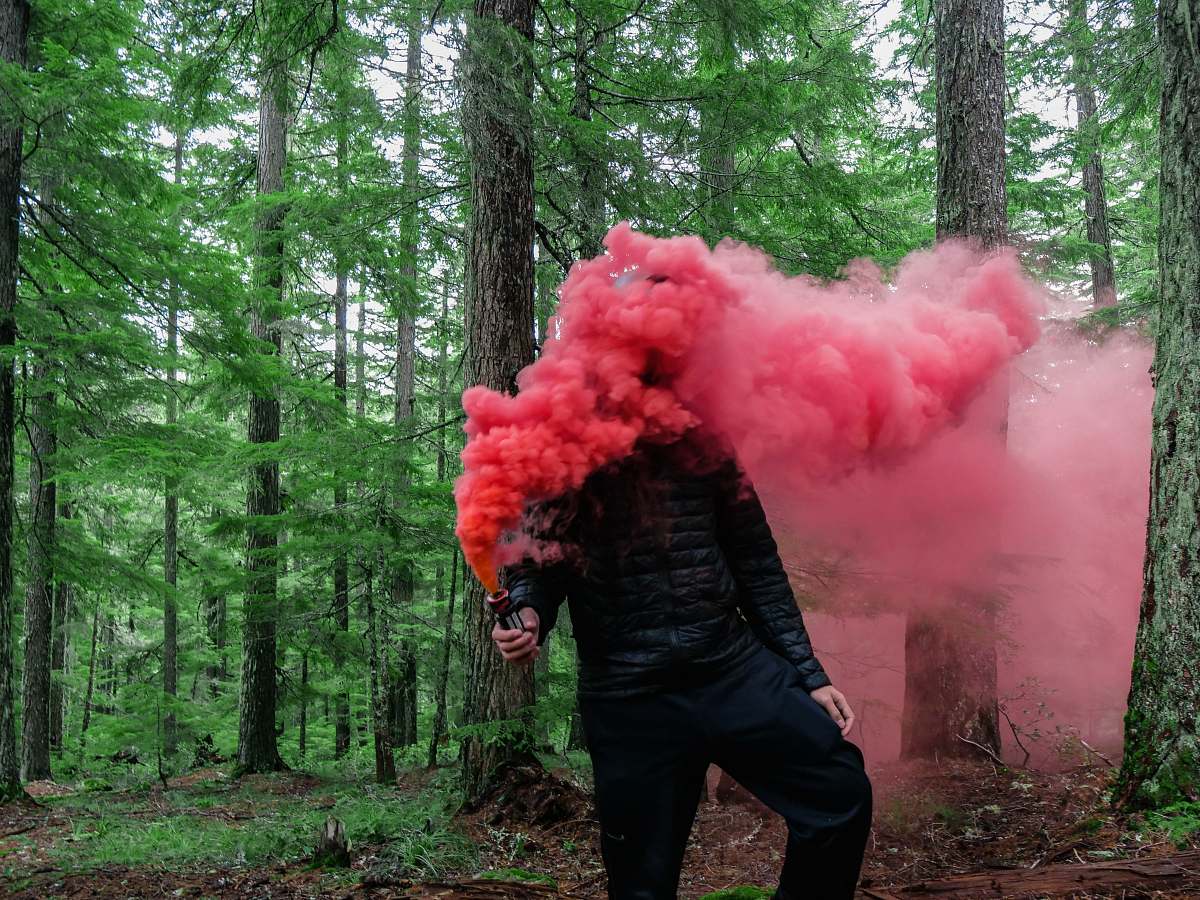 person person holding smoke grenade with red color smoke people