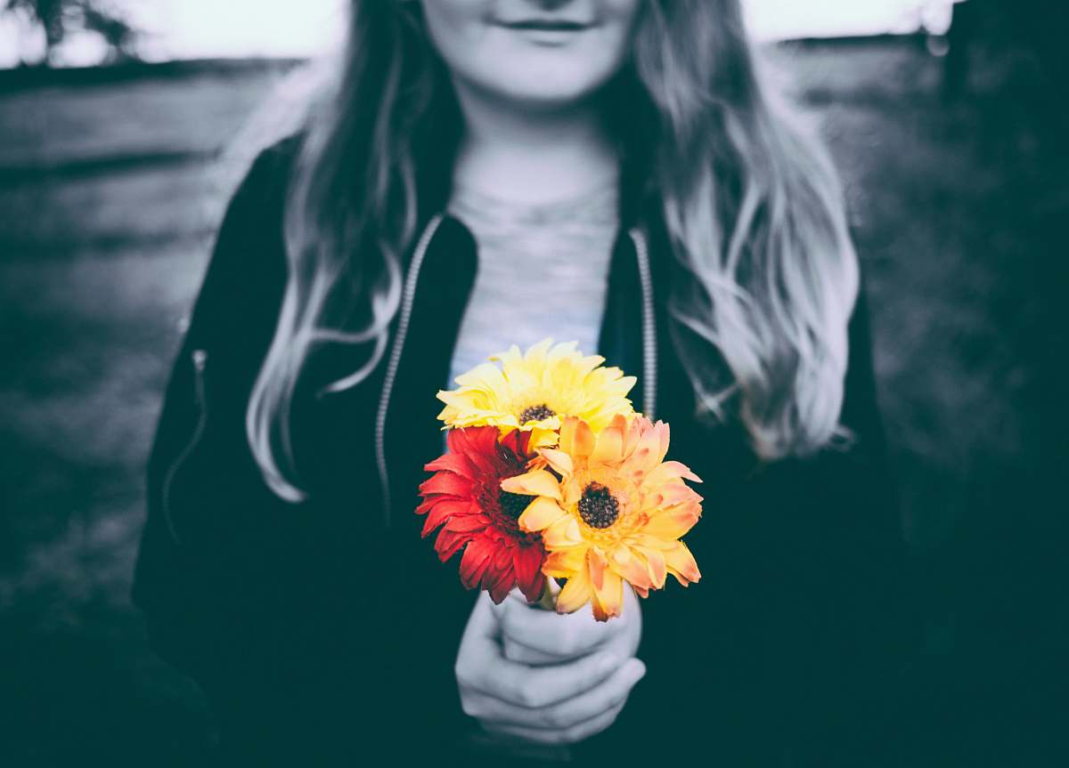 person selective-color photo of person holding yellow and red flowers woman