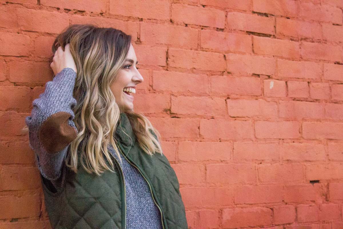 person woman holding her her while leaning on red brick wall brick